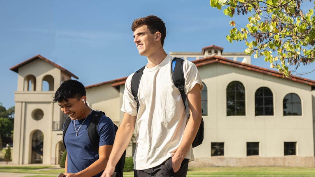 Two students walking to class past library